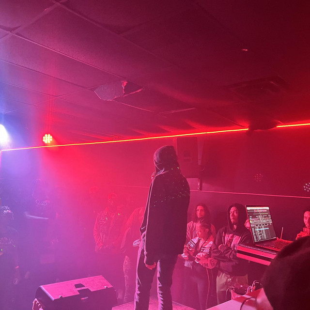 Cover of the single Hotel Lobby 9am: a performer on a red-lit stage